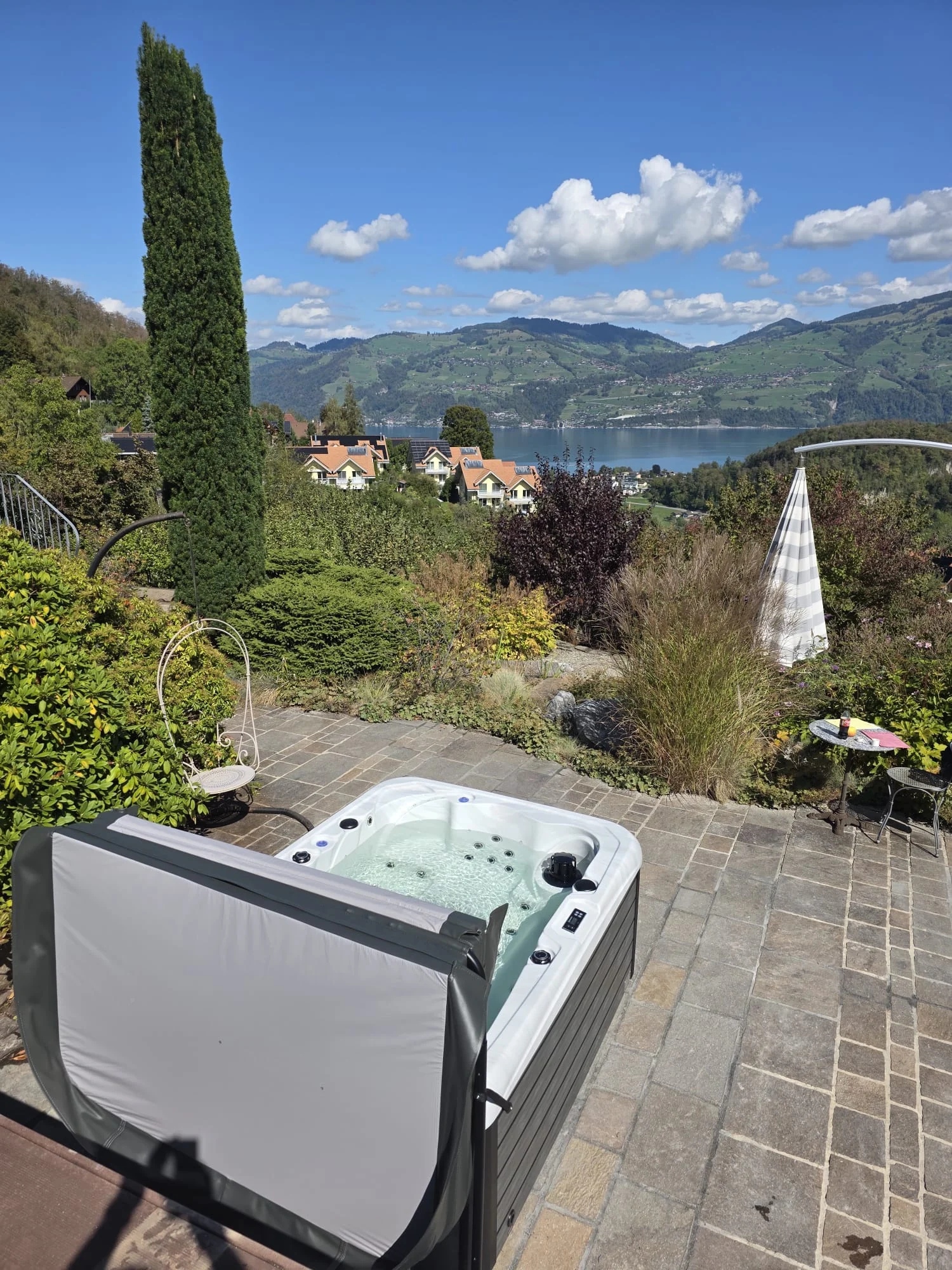 Idromassaggio con copertura aperta su una terrazza da giardino con vista sul lago