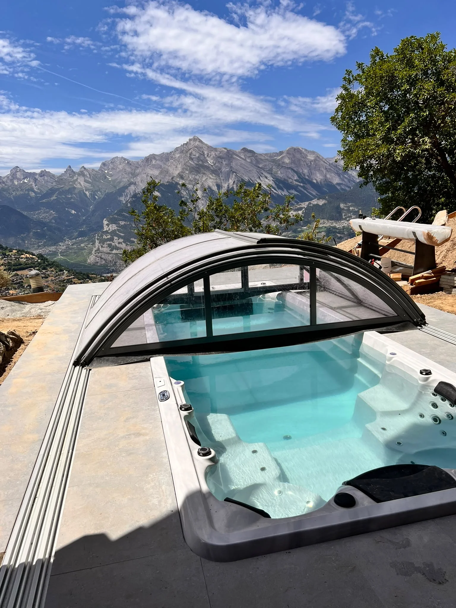 Swim spa incassato con copertura scorrevole davanti a un panorama montano