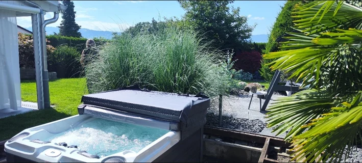 Idromassaggio in giardino con graminacee e palma