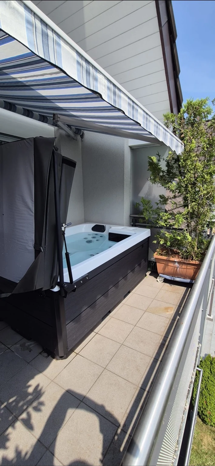 Idromassaggio su balcone sotto una tenda a righe