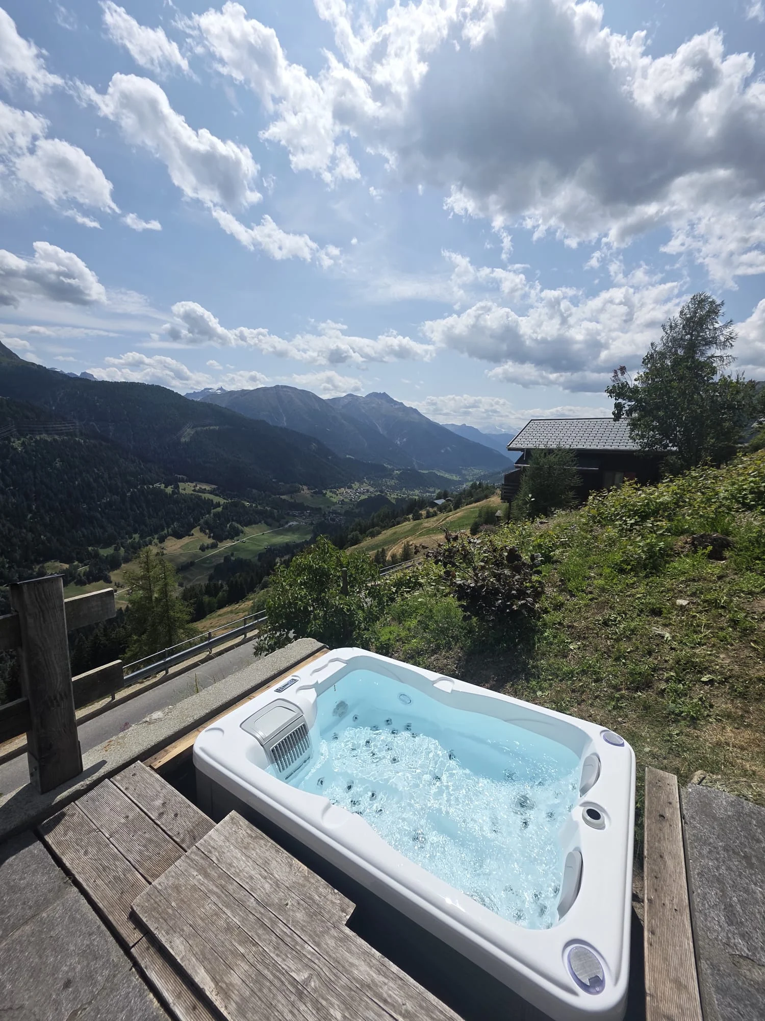 Idromassaggio incassato in una terrazza in legno davanti a un panorama montano